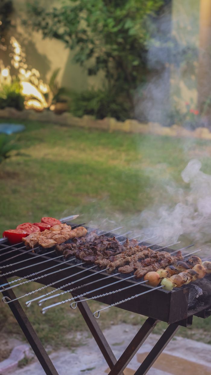 A backyard barbecue grill with smoky skewers of vegetables and meat in a relaxed outdoor setting.